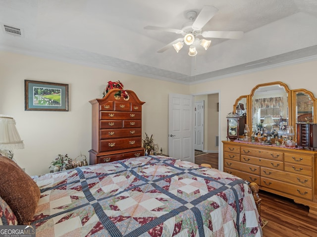 bedroom with visible vents, crown molding, a raised ceiling, and wood finished floors
