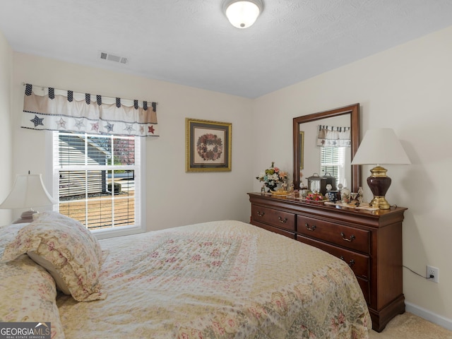 bedroom with visible vents, light carpet, and baseboards