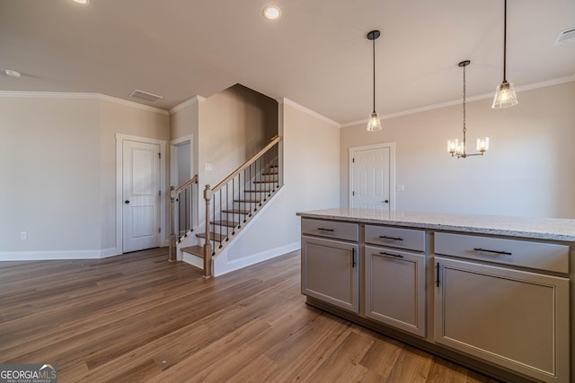 kitchen featuring gray cabinetry, baseboards, light wood finished floors, crown molding, and a chandelier