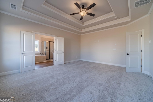 carpeted spare room featuring a raised ceiling, a ceiling fan, crown molding, and baseboards