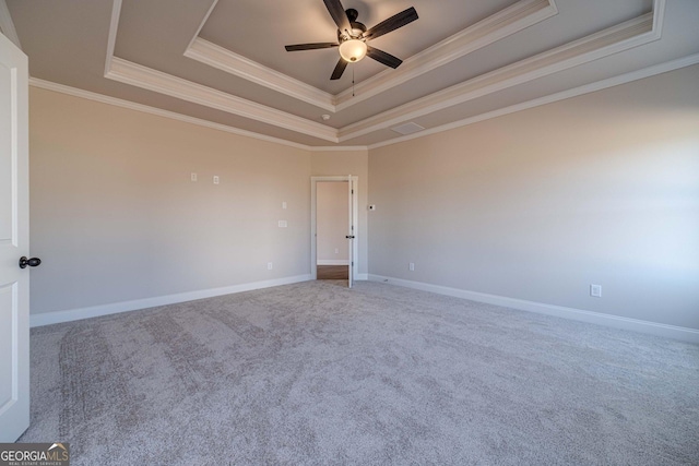 unfurnished room with a raised ceiling, ornamental molding, a ceiling fan, carpet flooring, and baseboards