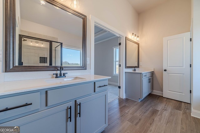 full bath with wood finished floors, a stall shower, two vanities, and baseboards