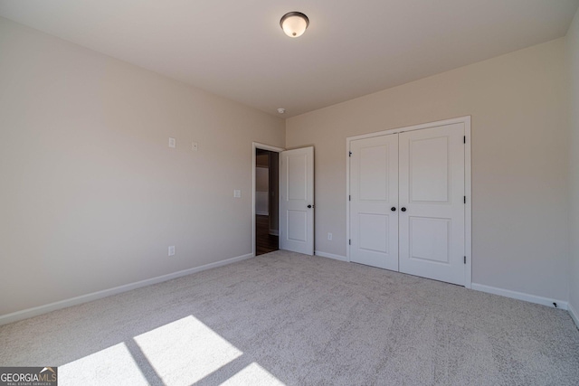 unfurnished bedroom with carpet floors, baseboards, and a closet
