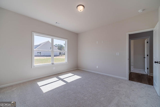 carpeted spare room with baseboards and a smoke detector