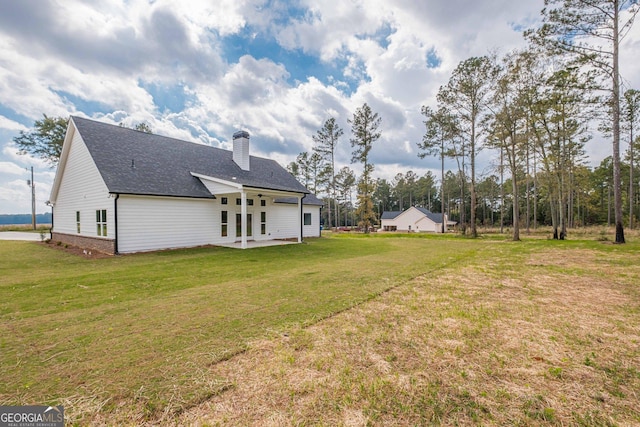rear view of house featuring a patio area, a chimney, ceiling fan, and a lawn