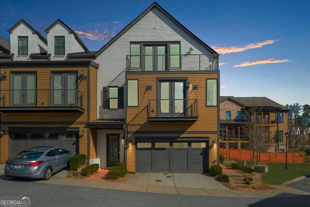 view of front of house featuring french doors, a balcony, and an attached garage