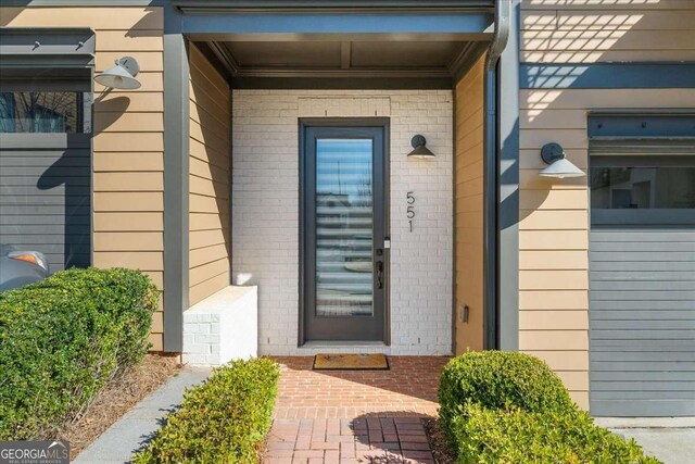 property entrance featuring a porch and brick siding