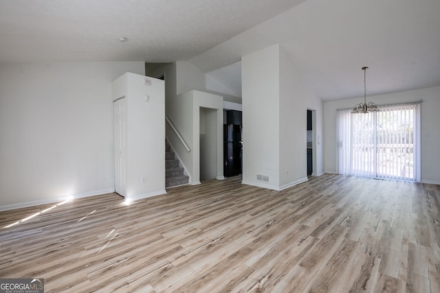 6136 Marbut Rd, Lithonia, GA 30058 - unfurnished living room featuring a chandelier, light wood finished floors, stairs, lofted ceiling, and baseboards