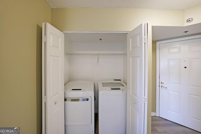 laundry area with wood finished floors, washing machine and dryer, laundry area, and a textured ceiling