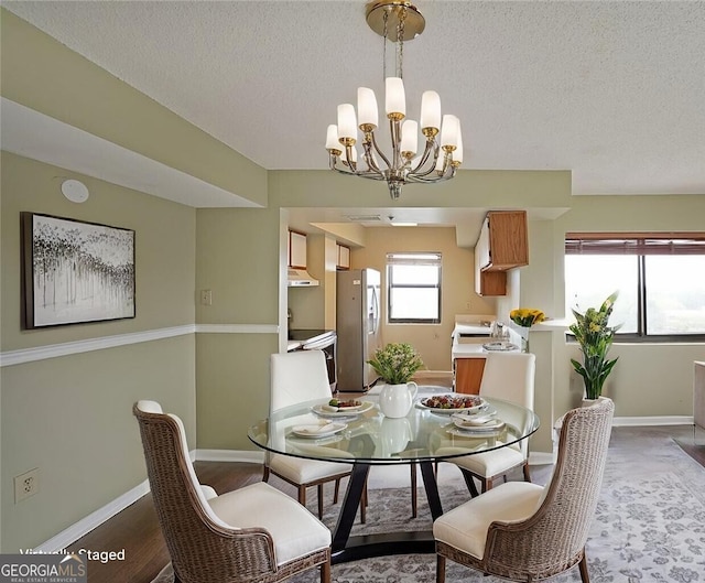 dining space featuring a notable chandelier, a textured ceiling, and baseboards
