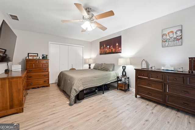 bedroom featuring light wood finished floors, visible vents, a closet, baseboards, and ceiling fan