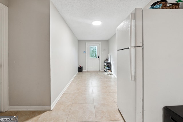 doorway featuring a textured ceiling, baseboards, and light tile patterned floors