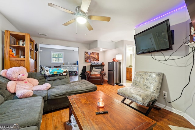 living room featuring light wood finished floors, baseboards, a ceiling fan, and visible vents