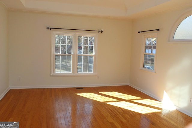 unfurnished room with hardwood / wood-style floors, visible vents, baseboards, and ornamental molding