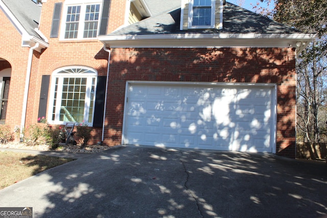 view of home's exterior featuring driveway, brick siding, and an attached garage