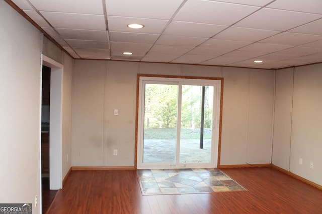 empty room featuring recessed lighting, a paneled ceiling, baseboards, and wood finished floors