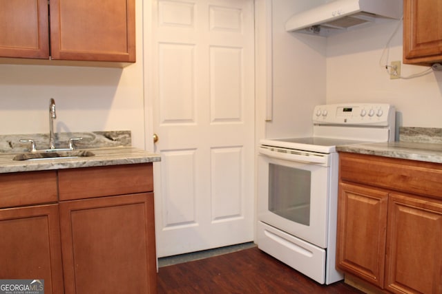 kitchen with white range with electric cooktop, dark wood-style flooring, a sink, under cabinet range hood, and brown cabinets