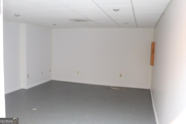 empty room featuring a paneled ceiling and concrete floors