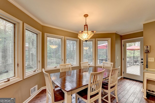 dining area featuring wood finished floors, baseboards, ornamental molding, and visible vents