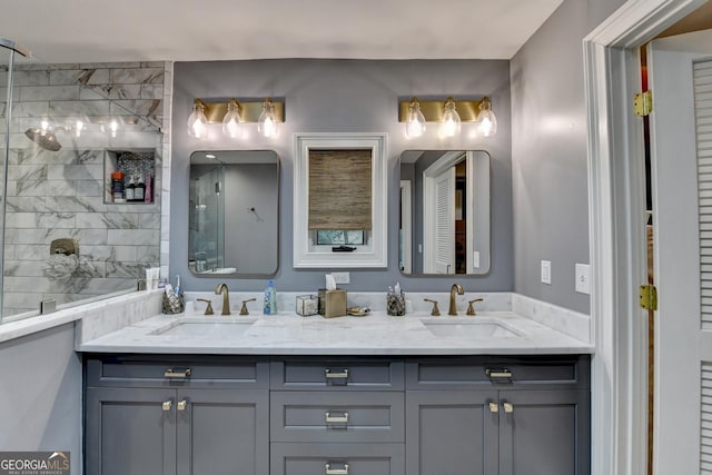 bathroom featuring double vanity, a tile shower, and a sink