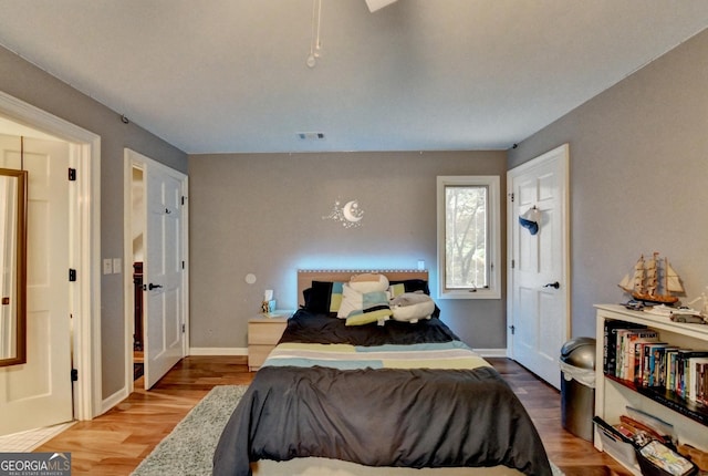 bedroom with wood finished floors, baseboards, and visible vents