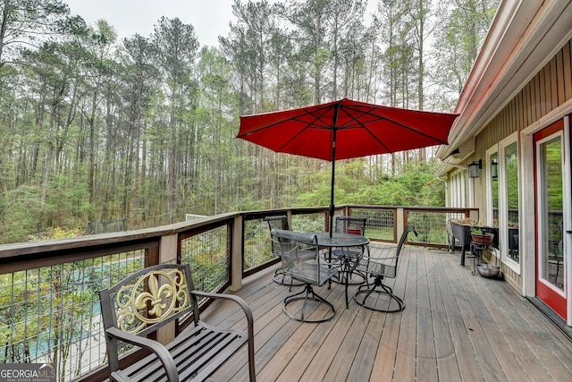 wooden terrace featuring a wooded view and outdoor dining area