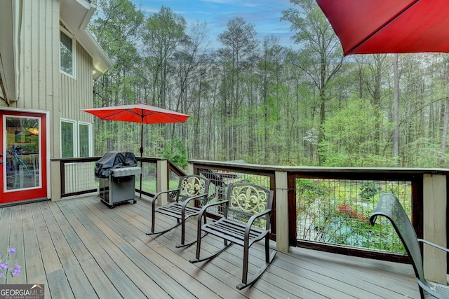 wooden deck featuring area for grilling and a forest view