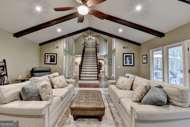 living area with stairway, a ceiling fan, beam ceiling, high vaulted ceiling, and wood finished floors
