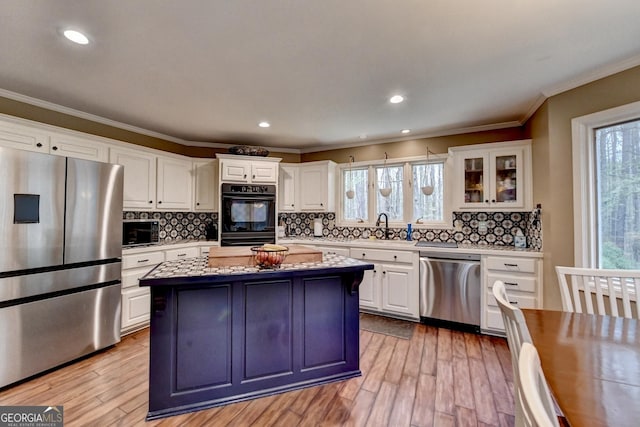 kitchen featuring stainless steel appliances, light wood-style floors, a center island, and a sink