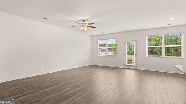 empty room featuring baseboards, visible vents, dark wood-style floors, and ceiling fan