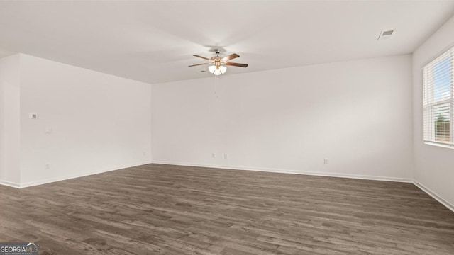 empty room with visible vents, a ceiling fan, baseboards, and dark wood-style flooring