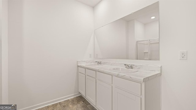 bathroom featuring baseboards, a sink, and double vanity