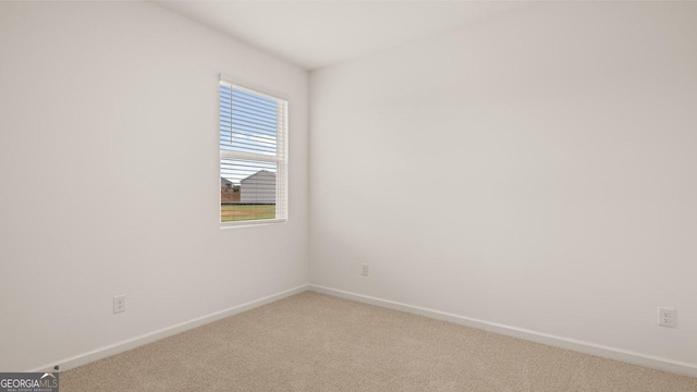 spare room featuring baseboards and light carpet