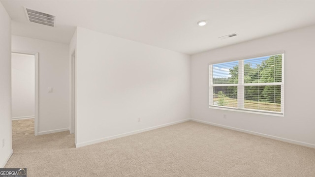 empty room featuring baseboards, visible vents, and light colored carpet