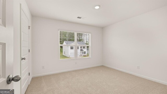 empty room with baseboards, visible vents, and carpet