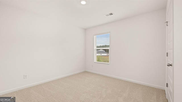 empty room featuring baseboards, visible vents, and light colored carpet