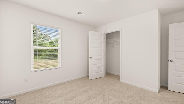 unfurnished bedroom with light carpet, a closet, visible vents, and baseboards