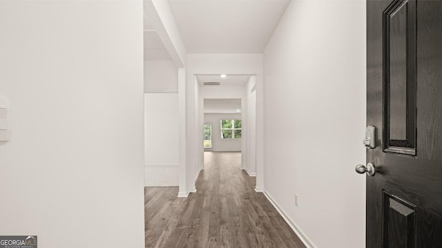 hall with wood finished floors, visible vents, and baseboards