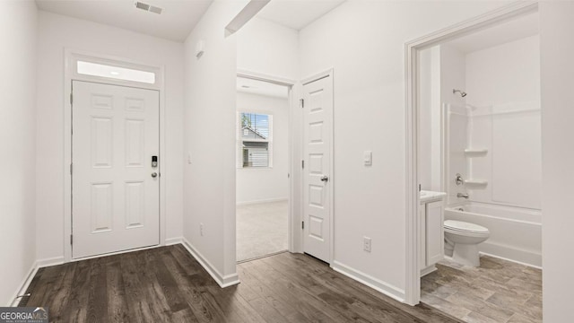foyer entrance with baseboards, wood finished floors, and visible vents