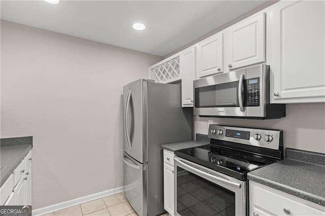 kitchen featuring dark countertops, white cabinets, appliances with stainless steel finishes, and baseboards