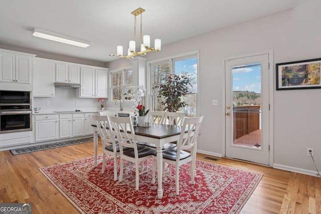 dining space featuring a notable chandelier, baseboards, and light wood finished floors