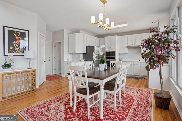dining space with baseboards, a notable chandelier, recessed lighting, and light wood-type flooring