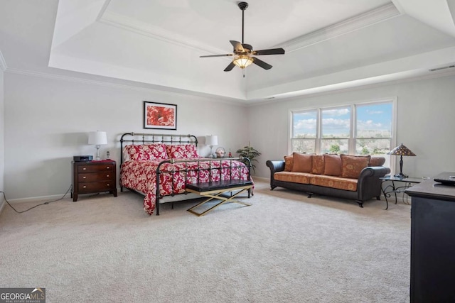 carpeted bedroom featuring a tray ceiling, crown molding, a ceiling fan, baseboards, and visible vents