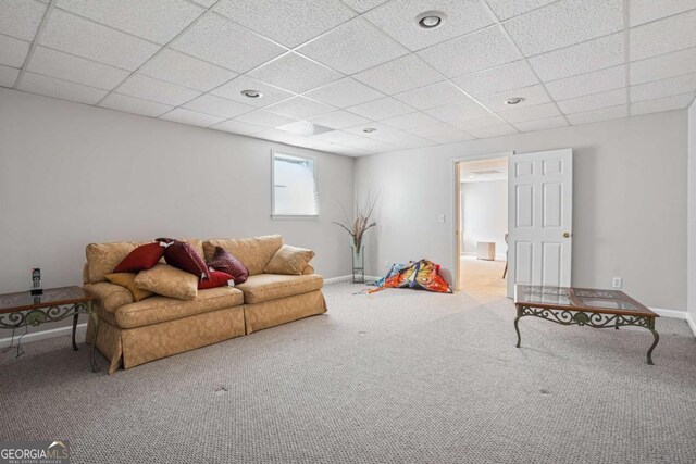 living room featuring carpet, baseboards, and a paneled ceiling