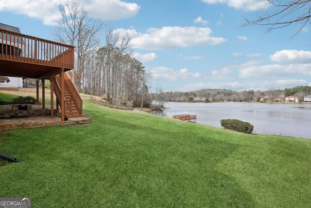 view of yard featuring a deck with water view and stairs