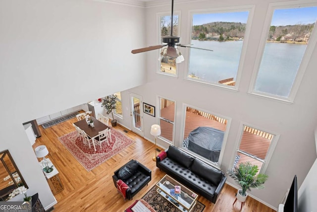 living area featuring a water view, a high ceiling, wood finished floors, and a ceiling fan