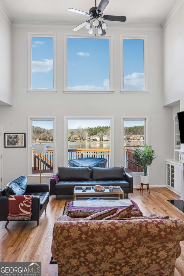 living area featuring a wealth of natural light, wood finished floors, ceiling fan, and ornamental molding