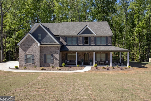 view of front of home featuring covered porch, a front yard, roof with shingles, and brick siding