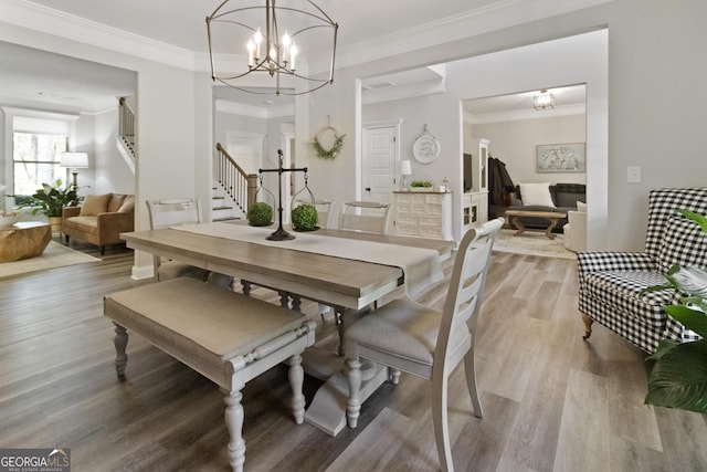 dining space featuring ornamental molding, a chandelier, stairs, and light wood-style flooring