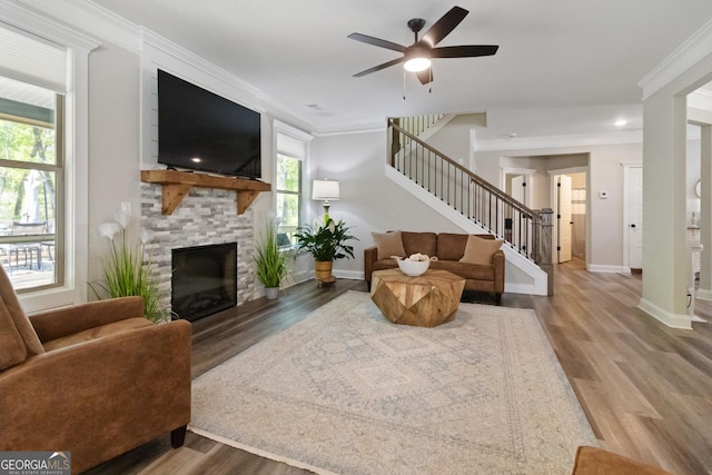 living room with wood finished floors, baseboards, a fireplace, stairs, and ceiling fan